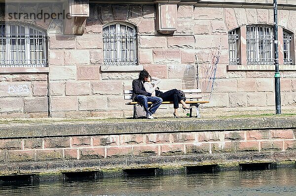 Bootsfahrt auf der L'ILL  Straßburg  Elsass  Zwei Personen sitzen entspannt auf einer Bank am Flussufer  Straßburg  Elsass  Frankreich  Europa