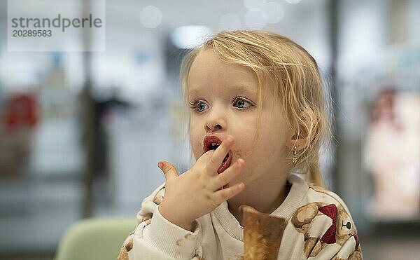Innenaufnahme  Mädchen  2-3 Jahre  blond  isst Schokoladeneis  Eis  Waffel  Mund verschmiert  Logo Apotheke  Stuttgart  Baden-Württemberg  Deutschland  Europa