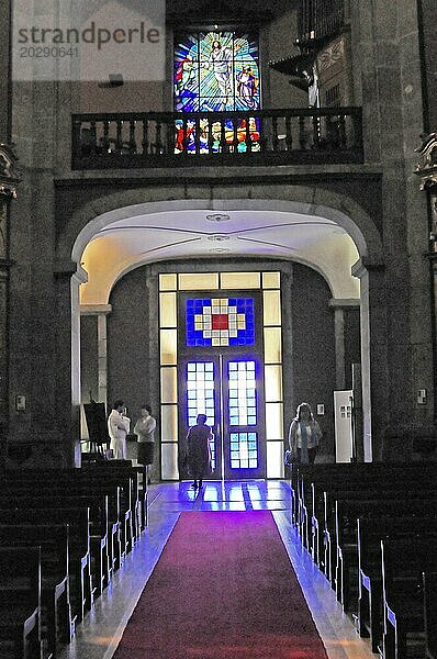 Die Kirche Igreja de Santo Ildefonso  Parca da Batalha  Porto  UNESCO Weltkulturerbe  Gegenlichtaufnahme eines Kirchenportals mit Menschen in Silhouette und modernem Buntglas  Nordportugal  Portugal  Europa