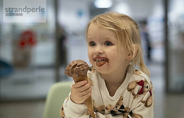 Innenaufnahme  Mädchen  2-3 Jahre  blond  isst Schokoladeneis  Eis  Waffel  Mund verschmiert  lächelt  fröhllich  Logo  Apotheke  Stuttgart  Baden-Württemberg  Deutschland  Europa