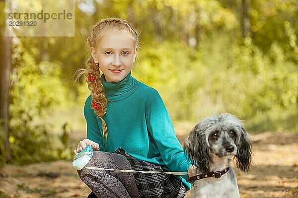 Porträt eines niedlichen lächelnden sommersprossigen Mädchens  das mit einem Hund posiert