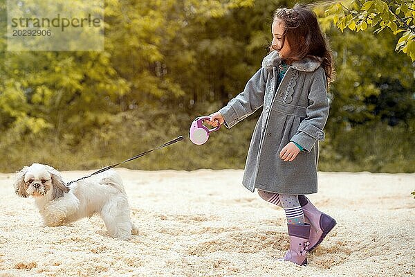 Bild von kleinen Fashionista zu Fuß mit Hund im Park