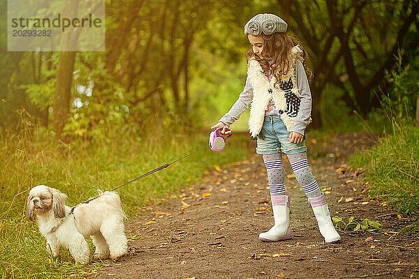 Bild von niedlichen lockiges Mädchen zu Fuß mit Hund im Park