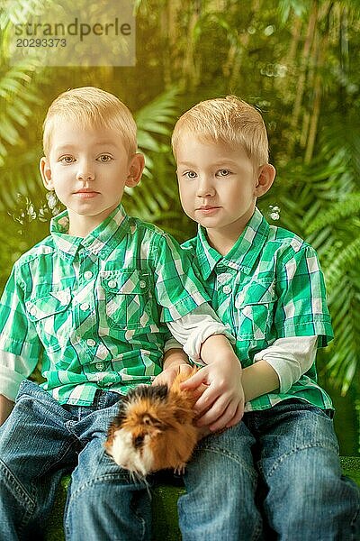 Bild von niedlichen jungen Zwillingen  die mit Meerschweinchen posieren  Nahaufnahme