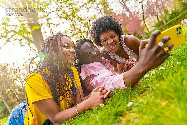 Afroamerikanische junge Freundinnen machen ein Selfie und liegen zusammen in einem Park