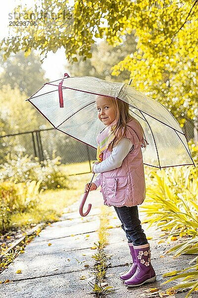 Verschmitzt lächelndes Mädchen posiert unter einem Regenschirm im Park  Nahaufnahme