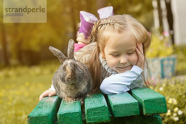 Niedliches Mädchen posiert auf Bank mit süßem Kaninchen  Nahaufnahme