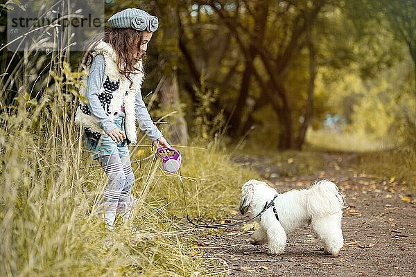 Bild von hübschen kleinen Mädchen spielen mit niedlichen Hund im Park