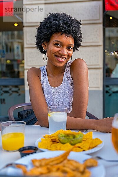 Cute Schönheit afrikanische Frau lächelnd in die Kamera sitzen in einem Fast Food mexikanischen Restaurant