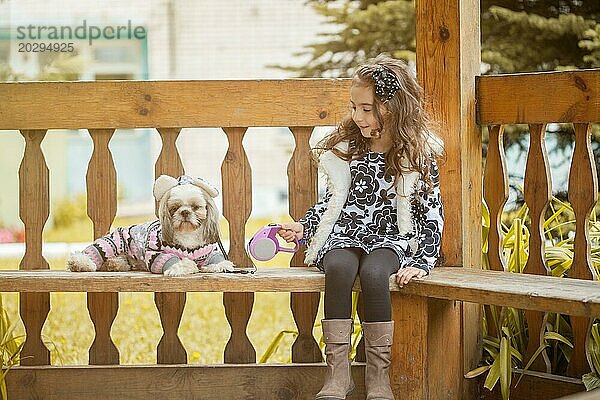 Lockiges Mädchen sitzt mit süßem Welpen in einer Laube  Nahaufnahme