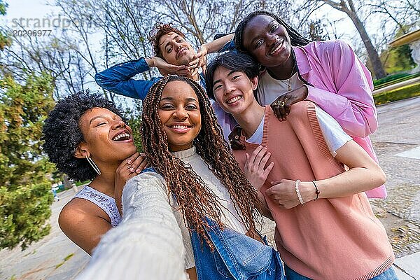 Persönliche Perspektive von fünf multiethnischen jungen Freunden  die bei einem Selfie in einem Stadtpark scherzen