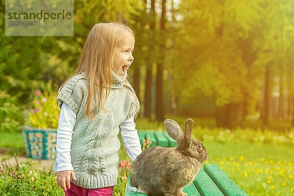 Fröhliches kleines Mädchen geht mit Kaninchen im Park spazieren  Nahaufnahme