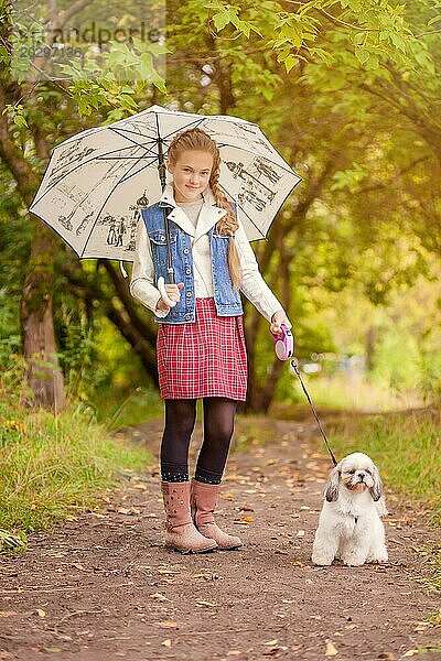 Charmantes kleines Mädchen mit süßem Hund im Regen spazieren