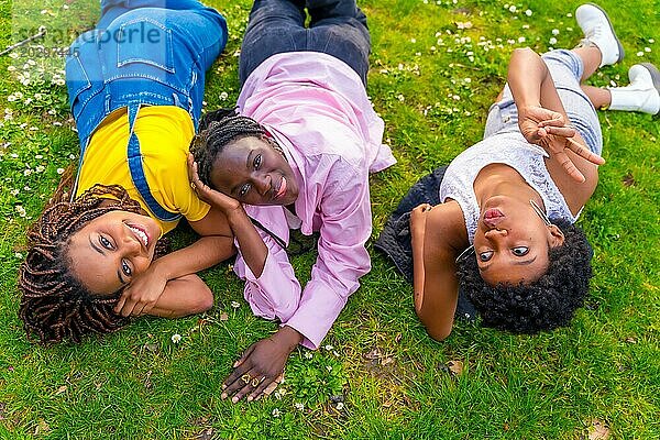 Entspannte afrikanische Frauen liegen in einem Park und genießen den Frühling