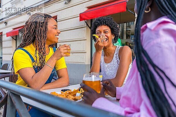 Junge  schöne afrikanische Freundinnen genießen eine Mahlzeit in einem Restaurant im Freien