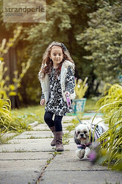 Spaziergang im Park  süßes kleines Mädchen hält ihren Hund an der Leine