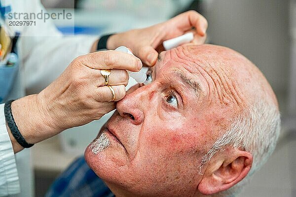 Ein Augenarzt gibt einem Mann während einer Glaukomuntersuchung Tropfen zur Erweiterung der Pupille