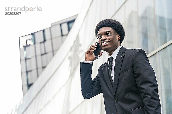 Niedrige Winkelansicht Nahaufnahme Porträt mit Kopie Raum eines jungen afrikanischen Geschäftsmann mit Telefon in der Stadt