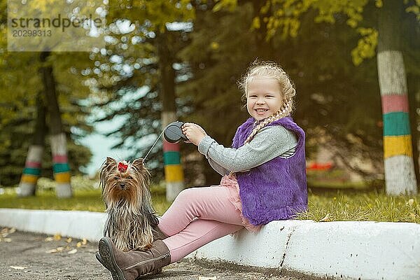 Bild des lächelnden kleinen blonden Mädchen posiert mit niedlichen Welpen