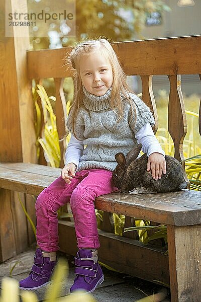 Hübsches kleines Mädchen sitzt im Pavillon mit Kaninchen  Nahaufnahme