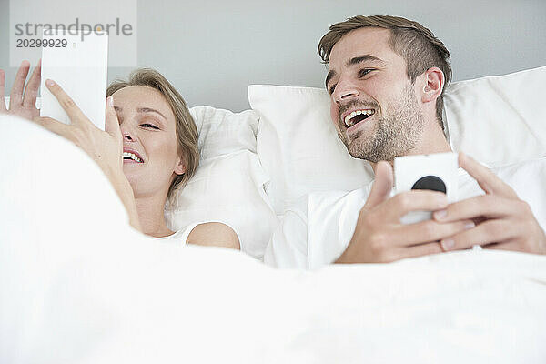 Paar im Bett mit Smartphone