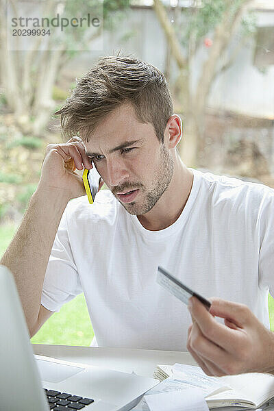 Mann benutzt Smartphone und hält Kreditkarte in der Hand