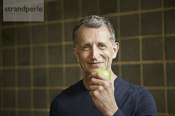 Reifer Mann hält einen Apfel