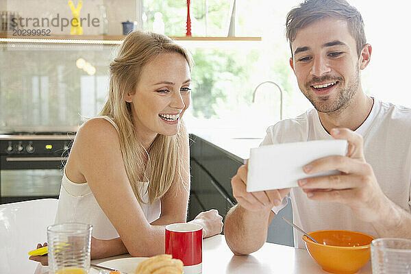 Paar beim Frühstück mit Smartphone