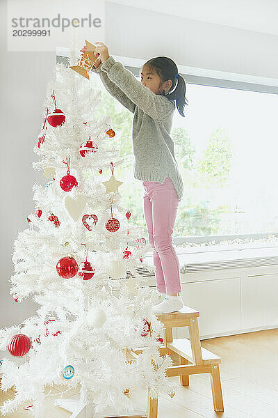 Junges Mädchen schmückt den Weihnachtsbaum