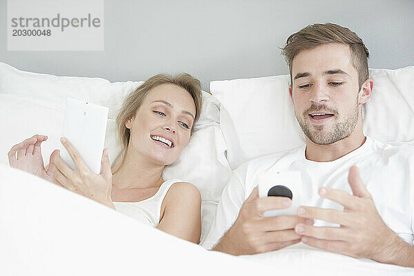 Paar im Bett mit Smartphone