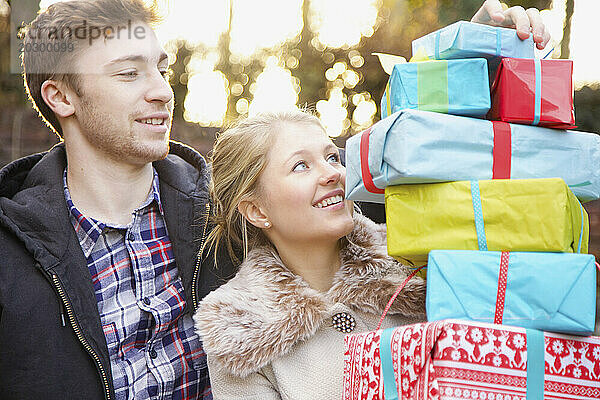 Junges Paar hält einen Stapel Weihnachtsgeschenke im Freien