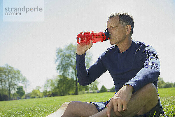 Reifer Mann trinkt aus Wasserflasche im Park