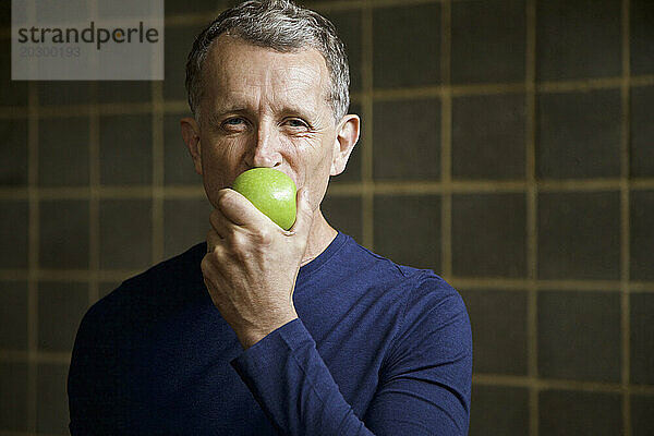 Reifer Mann beißt in einen Apfel