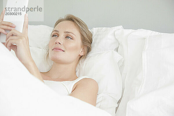 Frau im Bett mit Smartphone