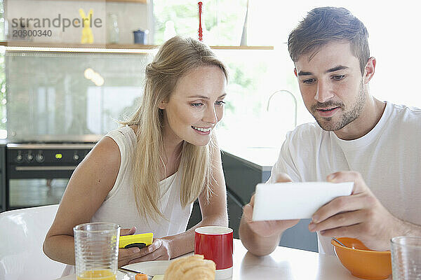 Paar beim Frühstück mit Smartphone