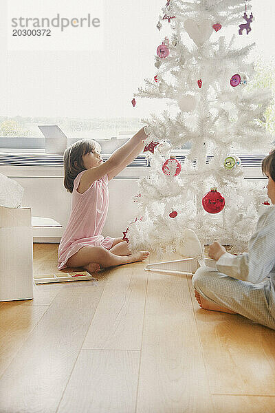 Junges Mädchen schmückt den Weihnachtsbaum