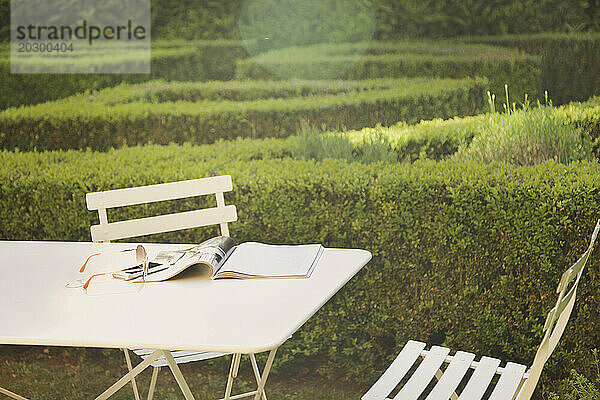 Zeitschrift und Sonnenbrille auf dem Tisch im Garten