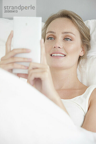 Frau im Bett mit Smartphone