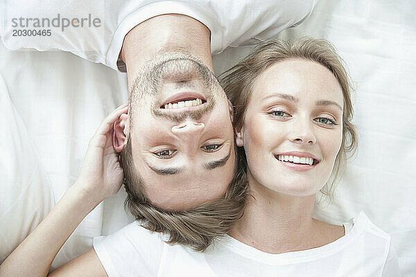 Lächelndes Paar liegt auf dem Bett und blickt in entgegengesetzte Richtungen