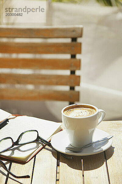 Cappuccino  Brillen und Notizblock auf dem Tisch im Freien