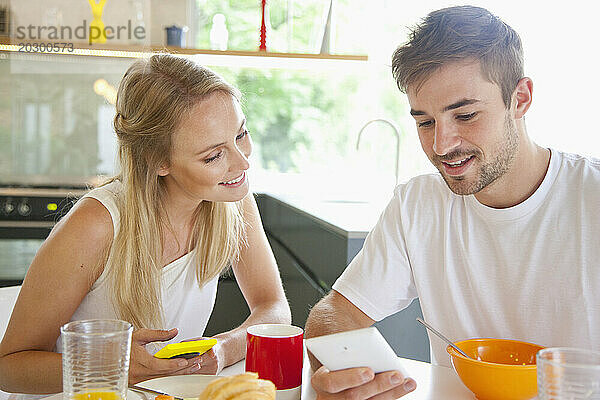 Paar beim Frühstück mit Smartphone