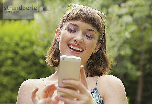 Lächelndes Teenager-Mädchen  das draußen Smartphone benutzt