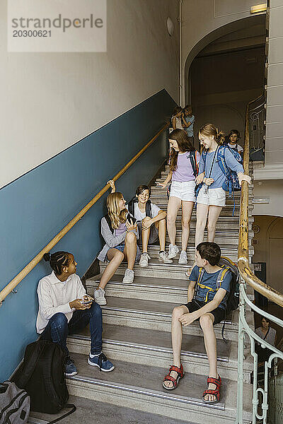 Männliche und weibliche Schüler auf der Treppe während der Pause in der Schule