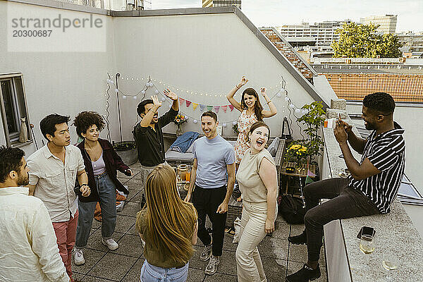 Mann fotografiert eine Gruppe Freunde  die auf dem Balkon auf einer Party tanzen