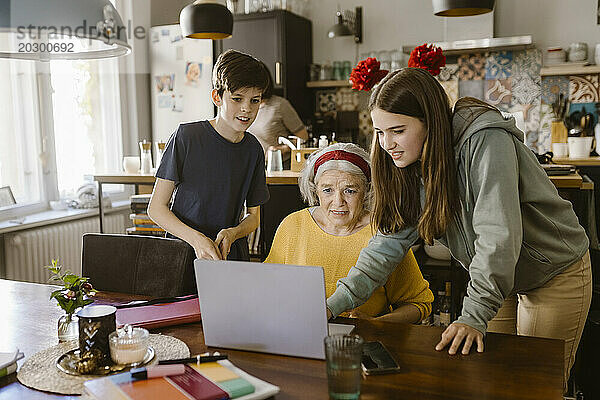 Mädchen benutzt Laptop mit Großmutter und Bruder zu Hause