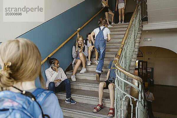 Männliche und weibliche Schüler haben Spaß auf Stufen in der Schule