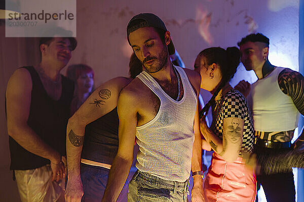 Schwule Person tanzt mit nicht-binären Freunden im Nachtclub