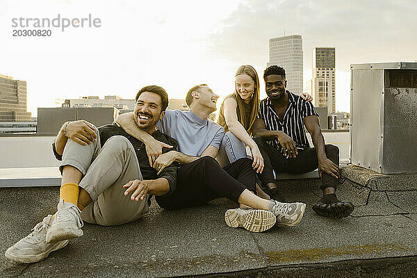 Fröhliche Gruppe männlicher und weiblicher Freunde  die Spaß haben  während sie auf der Terrasse sitzen