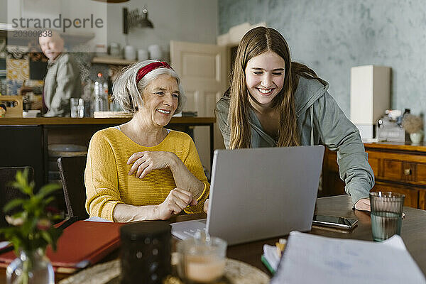 Glückliches Mädchen bringt Großmutter bei  zu Hause einen Laptop zu benutzen