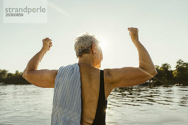 Rückansicht einer älteren Frau  die im Urlaub auf einem Hausboot ihre Muskeln spielen lässt